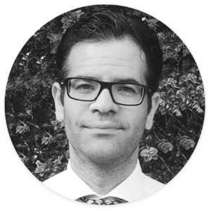 Portræt af en mand med briller og skjorte, der repræsenterer en inkassoadvokat, med fokus på professionel rådgivning til SMV-ejere.